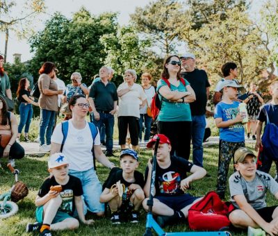 A diverse group of people enjoying a sunny day at an outdoor community event in a park setting.