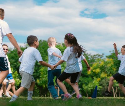 Group of children having fun and playing games together in a sunny park.